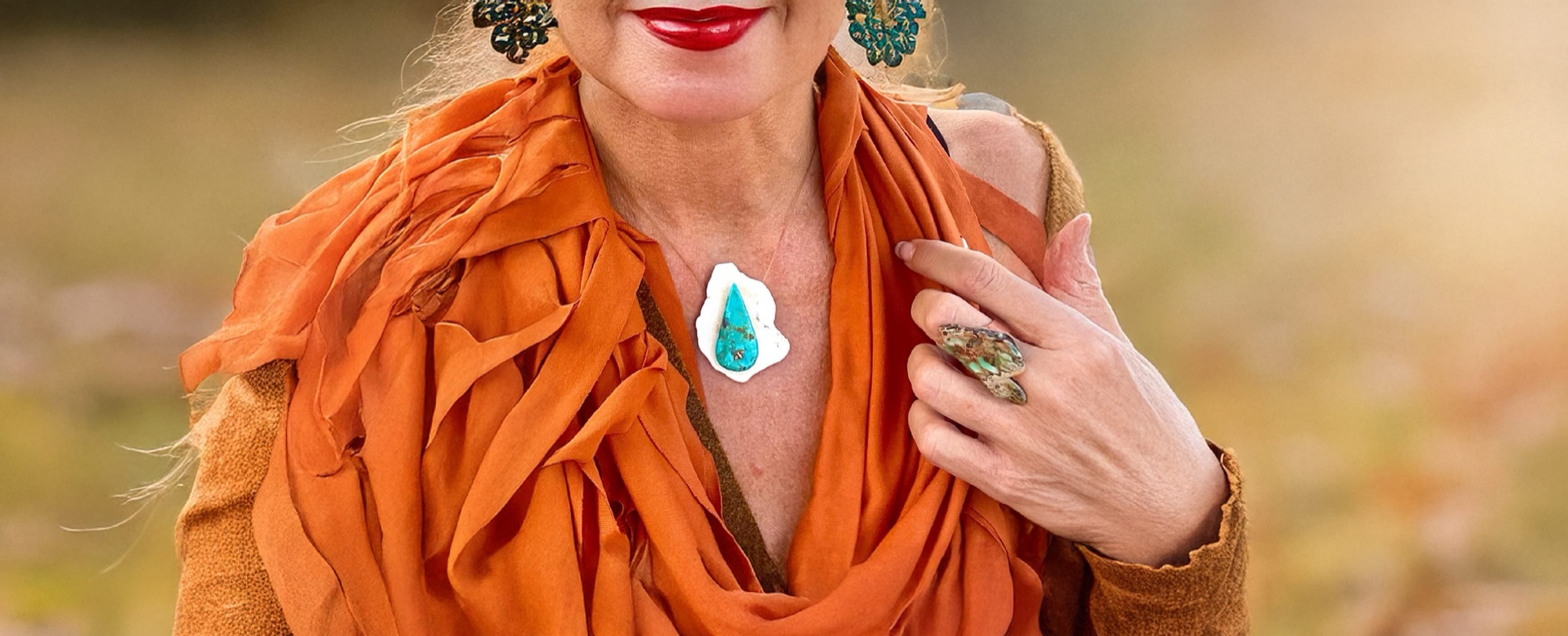 A woman in an orange scarf wearing a turquoise pendant on a clear cord and a turquoise ring